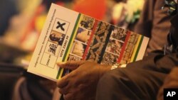 A supporter of Zimbabwean President Robert Mugabe holds a campaign card at Zanu-PF 13th annual conference in Gweru in December 2012. 