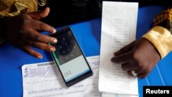 An official from Congo's Independent National Electoral Commission (CENI) uses his phone to calculate the numbers of presidential election votes at tallying center in Kinshasa, Democratic Republic of Congo, Jan. 4, 2019. 