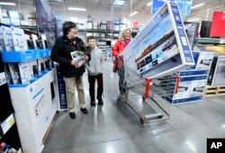 BJ's Wholesale Club members Linda Lupien of Marlborough, Mass. with grandson Jacob Lupien, 10 and his mother, Katy Lupien, of Shrewsbury, Mass., head toward the checkout counter with a new television during BJ's Black Friday sales event, Nov. 23, 2018, in Northborough, Mass.