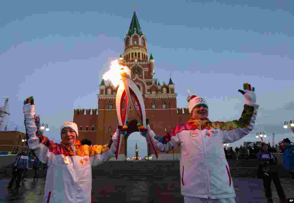 Torch bearers, Marina Tartyshnaya, left, and Musa Galyamov hold their torches during the Olympic torch relay in downtown Yoshkar-Ola, some 600 km (372 miles) east of Moscow, Russia. (Photo provided by Olympictorch2014.com)