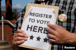 FILE - A man holds voter registration forms outside a campaign rally with U.S. Democratic presidential candidate Hillary Clinton in Greensboro, North Carolina, United States September 15, 2016.