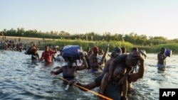 Мигранты из Гаити переходят вброд реку Рио-Гранде на границе между Мексикой и США. 20 сентября 2021г. 