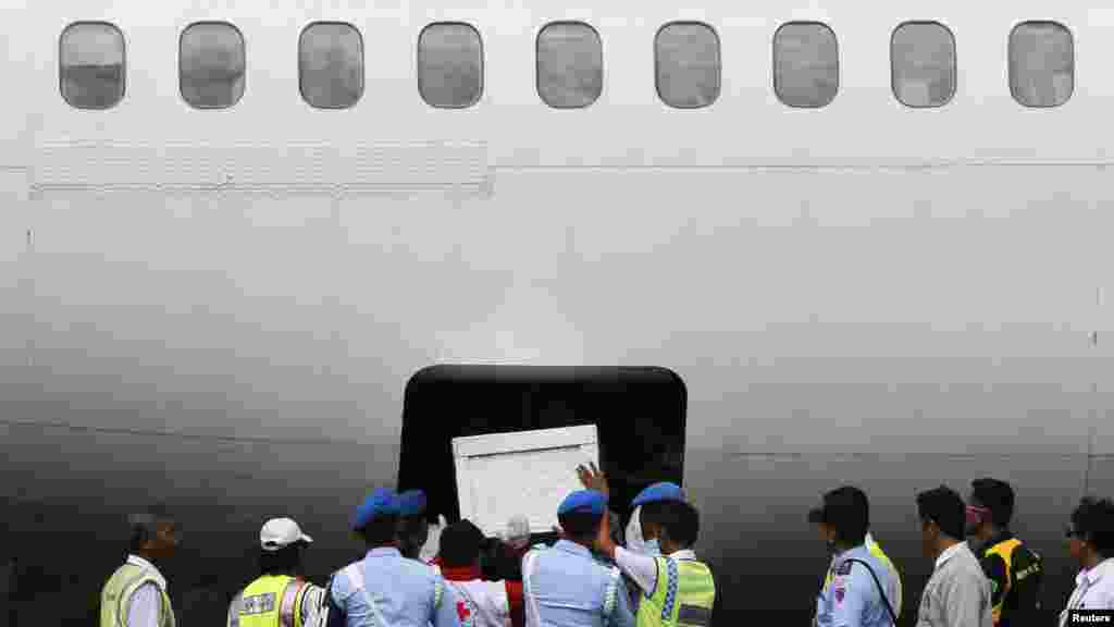 Des soldats indonésiens et les pompiers aident à placer le cercueil d&#39;un passager du vol AirAsia QZ8501 dans la soute d&#39;un avion Trigana au Iskandar base aérienne de Pangkalan Bun.