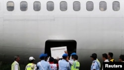 Indonesia soldiers and rescue personnel put a coffin of a passenger of AirAsia Flight QZ8501 into the cargo compartment of a Trigana airplane, file photo. 