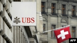 A Swiss flag is seen behind a sign of Swiss bank giant UBS on June 11, 2013 in Basel, Switzerland. 