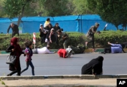In this photo provided by Mehr News Agency, civilians try to take cover in a shooting attack during a military parade in the southwestern city of Ahvaz, Iran, Sept. 22, 2018.
