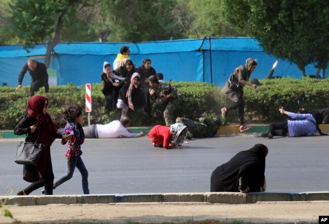 In this photo provided by Mehr News Agency, civilians try to take cover in a shooting attack during a military parade marking the 38th anniversary of Iraq's 1980 invasion of Iran, in the southwestern city of Ahvaz, Iran, Sept. 22, 2018.