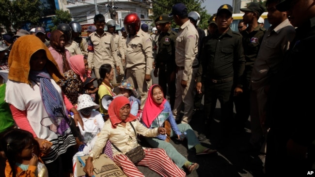 Farmers of Koh Kong province protesting land evictions are blocked by security during a protest rally as it moves near the Prime Minister's residence, in Phnom Penh, Cambodia, Tuesday, Feb. 14, 2017. Government security on Tuesday prevented the protesters from submitting a petition to Prime Minister Hun Sen at his residence to help solve their long-running land dispute with a local tycoon who owns sugarcane plantations they accuse of grabbing their land. (AP Photo/Heng Sinith)