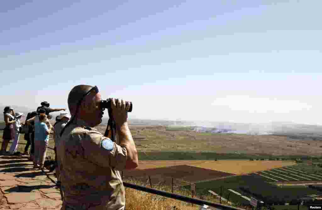 A U.N. peacekeeping soldier uses binoculars to watch fighting between forces loyal to and opposed to Syrian President Bashar al-Assad from the Golan Heights, June 7, 2013.