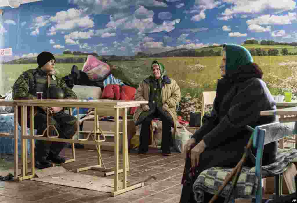 A soldier, left, guards as two elderly women wait to get a humanitarian aid in Avdiivka, eastern Ukraine.