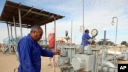 FILE - Workers check pipes and valves at Amaal oil field in eastern Libya, October 7, 2011. 