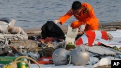 Član tima za spašavanje i potragu skuplja ostatke indonežanskog aviona