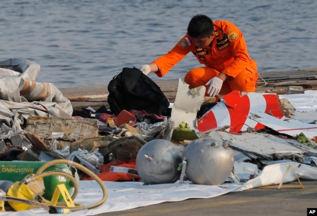 A member of Indonesian Search and Rescue Agency (BASARNAS) inspects debris believed to be from Lion Air passenger jet that crashed off Java Island at Tanjung Priok Port in Jakarta, Indonesia, Oct. 29, 2018.