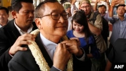 FILE - Sam Rainsy, foreground, leader of the opposition Cambodia National Rescue Party (CNRP), receives a garland of jasmine upon his arrival at Phnom Penh International Airport in Phnom Penh, Cambodia, Aug. 16, 2015.