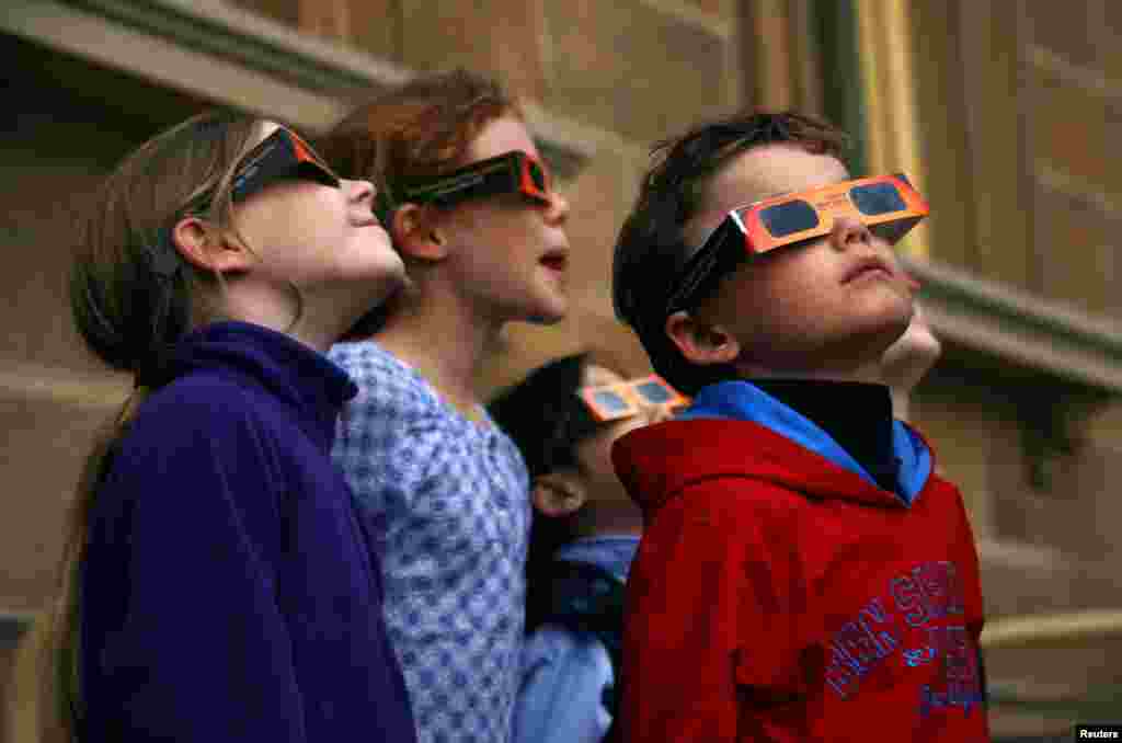 Children wear protective glasses as they try to see a partial solar eclipse from Sydney's Observatory Hill, Australia