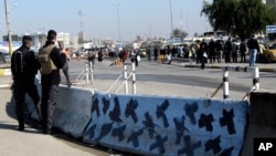 Iraqi security forces stand guard at the site of a bomb attack in Baghdad, Iraq, Jan. 12, 2014. 