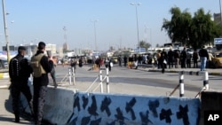 Iraqi security forces stand guard at the site of a bomb attack in Baghdad, Jan. 12, 2014.