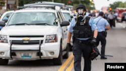 FILE - Police wear gas masks as they attempt to disperse a crowd that gathered after a shooting incident in St. Louis, Missouri August 19, 2015. 