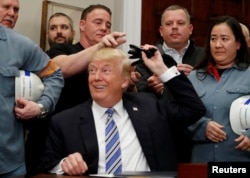 U.S. President Donald Trump gives out pens he used to sign presidential proclamations placing tariffs on steel and aluminum imports to workers from the steel and aluminum industries at the White House in Washington, March 8, 2018.