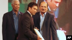 Indian cricketer Sachin Tendulkar, center, holds an autographed bat presented to him, as former West Indies cricketer Gary Sobers, left, and former Indian cricketer Ajit Wadekar watch, in Mumbai, India, Thursday, March 4, 2010. These are not familiar names to most Americans. 