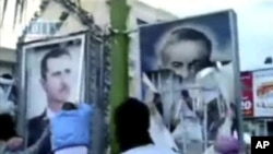 In this image taken from amateur video posted on the Internet by Shaam News Network, protesters in the northeastern town of Qamishli, Syria, tear down billboards with photos of President Bashar Assad, left, and his father Hafez Assad, April 29, 2011