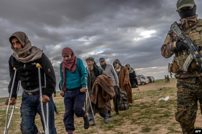 Men suspected of being Islamic State fighters wait to be searched by members of the Kurdish-led Syrian Democratic Forces (SDF) after leaving the IS group's last holdout of Baghuz, in Syria's northern Deir Ezzor province, Feb. 27, 2019.