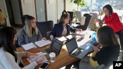 In this January 16, 2019 photo, ModernWell founder Julie Burton, right, arranges flowers as four women discuss plans for a non-profit event in Minneapolis.(AP Photo/Jim Mone)