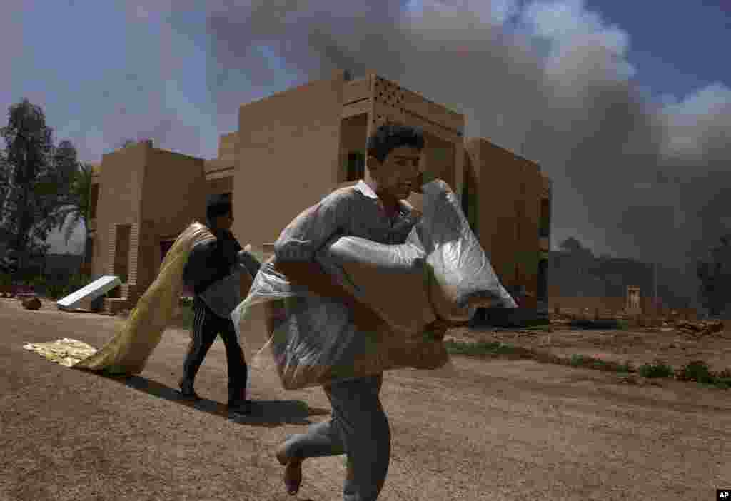 Iraqi men run through a neighborhood with looted items, Baghdad, April 10, 2003.