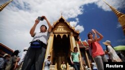 Tourists take pictures as they visit the Grand Palace in Bangkok