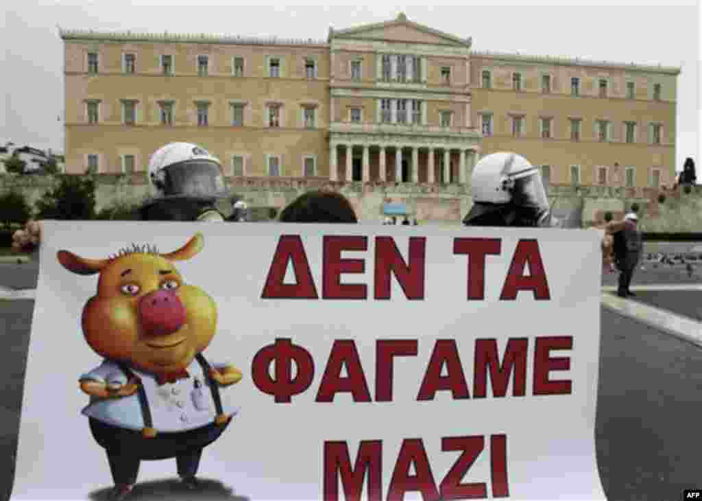 A protester holds a banner reading, "We didn't binge together", during a rally outside the Greek Parliament in Athens, Wednesday, Dec. 15, 2010. Hundreds of protesters clashed with riot police across central Athens Wednesday, smashing cars and hurling gas