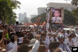 Cambodia mourners take photos as they watch the funeral procession for Cambodian leading government critic Kem Ley, whose portraits are displayed on a vehicle, in Phnom Penh, July 24, 2016.