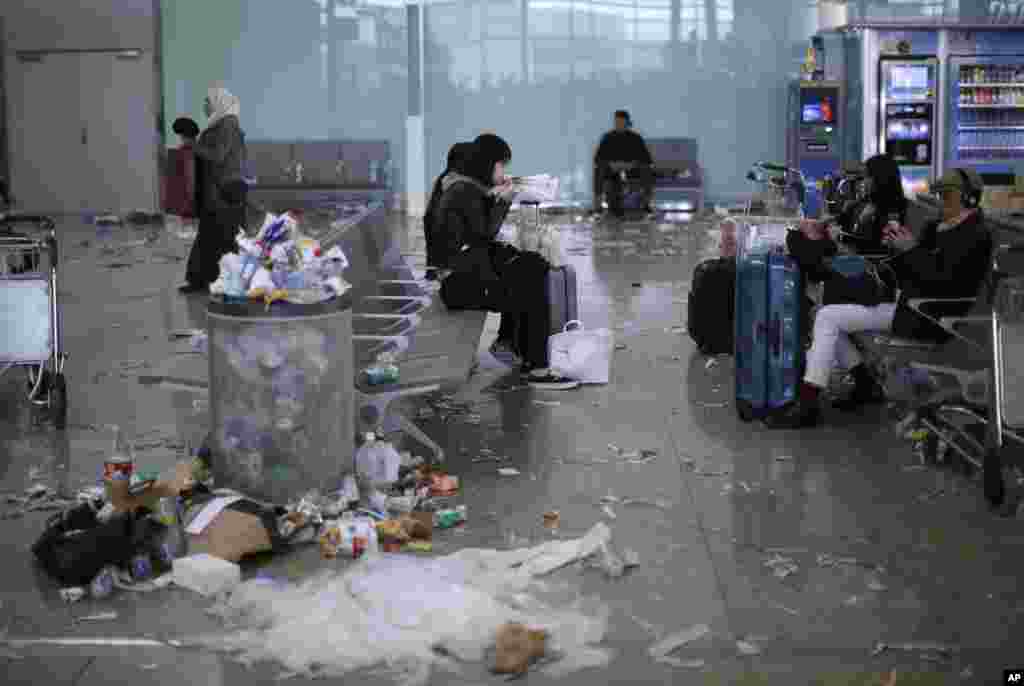 Passengers sit surrounded by rubbish and papers thrown by cleaning workers as they hold the fourth day of a strike at Barcelona airport in Prat Llobregat, Spain.