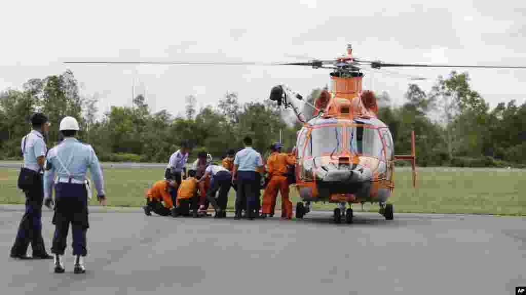 Oficiais da Agência de Busca e Salvamento da Indonésia (BASARNAS) e a Força Aérea Indonésia tiram do helicóptero o corpo de uma vítima do avião da AirAsia QZ 8501. O avião da Air Asia caiu a 28 de Dezembro. Indonésia Dez. 31, 2014.