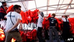 Les membres de SOS-Méditerranée portent des gilets de sauvetage sur le navire de secours Aquarius, au cours de l’opération de recherche et de sauvetage, en haute mer, entre l'Algérie et Tunisie, le 22 juin 2018.