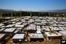 Syrian refugees walk outside their tents at a Syrian refugee camp in the town of Bar Elias, in Lebanon's Bekaa Valley, April 23, 2018.
