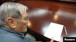 In image released by North Korea's Korean Central News Agency (KCNA), U.S. citizen Merrill E. Newman puts thumbprint on paper after being taken into custody by North Korea as tourist, undisclosed, Nov. 30, 2013.