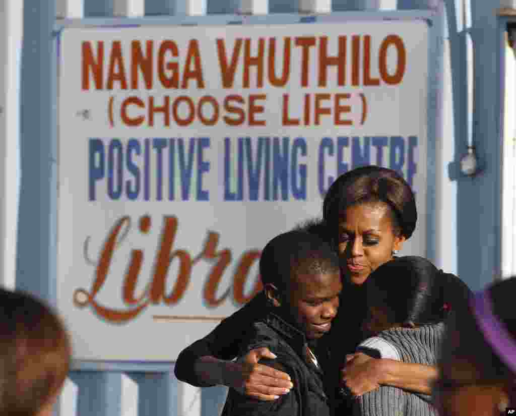 Michelle Obama abraça crianças numa visita ao Centro Comunitário Vhuthilo, no Soweto.