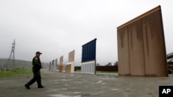 FILE - A Border Patrol agent walks towards prototypes for a border wall in San Diego, California, Feb. 5, 2019. 