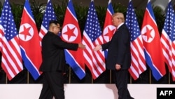 지난 6월 싱가포르에서 열린 첫 미-북 정상회담에서 도널드 트럼프 미국 대통령과 김정은 북한 국무위원장이 서로에게 손을 내밀고 있다.