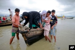 Bangladeshi villagers help two elderly Rohingya women from a boat after crossing a canal at Shah Porir Deep, in Teknak, Bangladesh, Aug. 31, 2017.