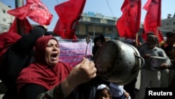 A Palestinian woman holds a cooking pot during a protest against a U.S. decision to cut funding to the U.N. Relief and Works Agency (UNRWA), outside an aid distribution center, in Khan Younis in the southern Gaza Strip, Sept. 4, 2018. On Sept. 8, the U.S. State Department said $25 million earmarked for the care of Palestinians in East Jerusalem hospitals would be directed elsewhere. 