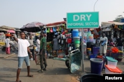 Men stand near displayed merchandise for sale around the informal sector at the Wuse market in Abuja, Nigeria, Jan. 30, 2018.