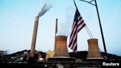 FILE - The U.S. flag flies on towboat M.K. McNally as it passes Mitchell Power Plant, a coal-fired power plant operated by American Electric Power, on the Ohio River in Moundsville, West Virginia, Sept. 10, 2017. 