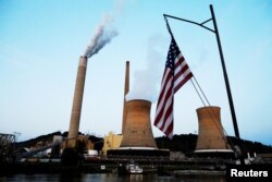 FILE - The U.S. flag flies on towboat M.K. McNally as it passes Mitchell Power Plant, a coal-fired power-plant operated by American Electric Power, on the Ohio River in Moundsville, West Virginia, Sept. 10, 2017.