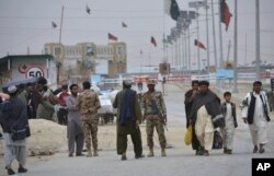 FILE - Pakistani paramilitary soldiers stand guard while people wait for opening border crossing, in Chaman, Pakistan, March 20, 2017.