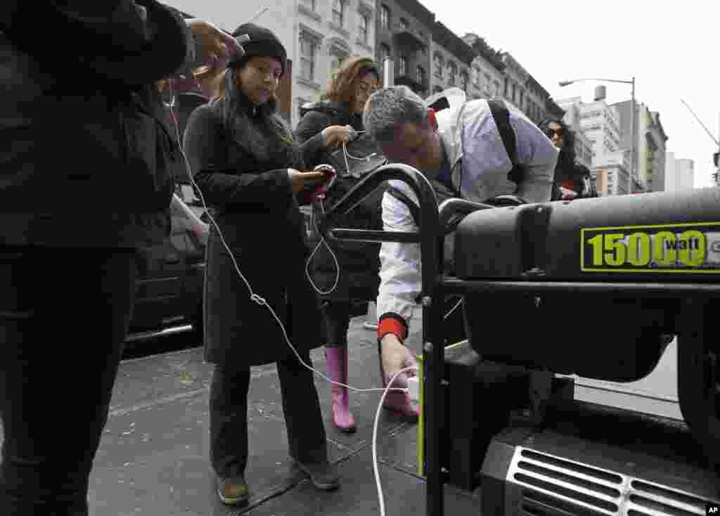 Sans &eacute;lectricit&eacute;, les habitants du quartier Tribeca de New York attendent de recharger leur t&eacute;l&eacute;phone portable &agrave; l&#39;aide d&#39;un groupe &eacute;lectrog&egrave;ne install&eacute; dans la rue&nbsp; 