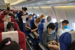 A flight attendant assists a passenger to fill in his travel history following the coronavirus disease (COVID-19) outbreak, on a China Eastern Airlines flight at Shenzhen Baoan International Airport in Shenzhen, Guangdong province, China May 19, 2020.