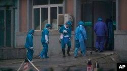 Hospital staff wash the emergency entrance of Wuhan Medical Treatment Center, where some infected with a new virus are being treated, in Wuhan, China, Wednesday, Jan. 22, 2020.