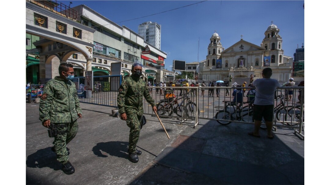 Polisi berpatroli saat umat Katolik Roma berkumpul di depan gereja Quiapo dalam perayaan Jumat Agung di Manila, 2 April 2021. Pemerintah Filipina kembali memberlakukan lockdown untuk mengatasi lonjakan infeksi COVID-19. (Foto:Jam STA ROSA / AFP)