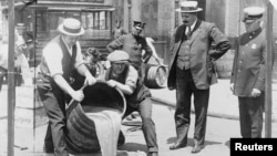 New York City Deputy Police Commissioner John A. Leach (R) watches agents pour liquor into a sewer following a raid during the height of prohibition in an undated photo held by the Library of Congress. 